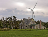 An old abandoned  house in Prince Edward Island contrasts with the modern wind turbine.