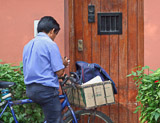 The mailman delivers the mail by bicycle in the city of Lima.